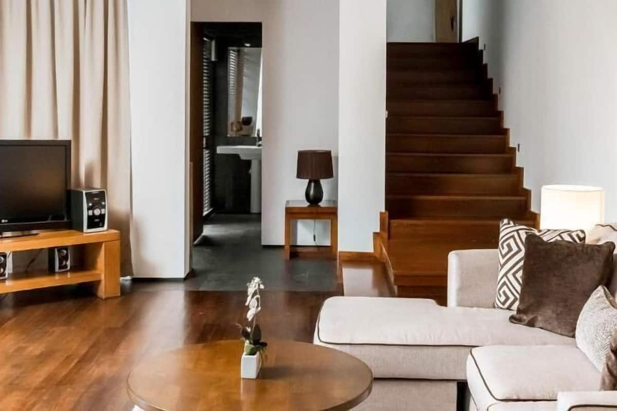 Ein Wohnzimmer mit einer Couch, einem Couchtisch, einem Fernseher und einer Treppe.