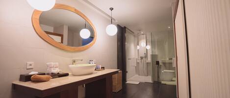 A modern bathroom with a large mirror, a wooden vanity, a large sink, and a glass shower enclosure.