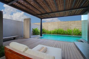 Un espace aménagé au bord de la piscine, avec une terrasse en bois, une chaise longue et une piscine.