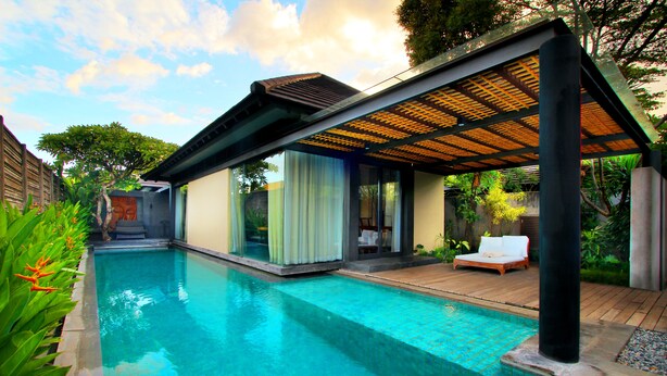 A modern poolside area with a clear pool, a covered seating area, and a view of the surrounding greenery. - Javana Royal Villas (Keroboken Kelod)