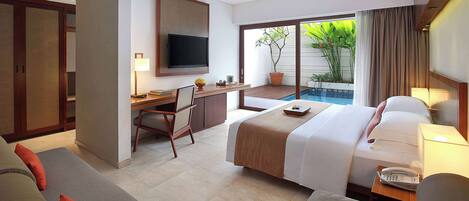 Habitación de hotel con cama, escritorio, televisor y vista a una piscina.