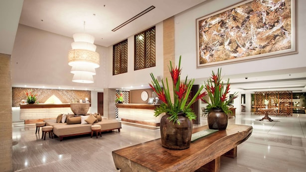 A modern lobby with a reception desk, seating area, and decorative plants. - The Magani Hotel and Spa (Legian)