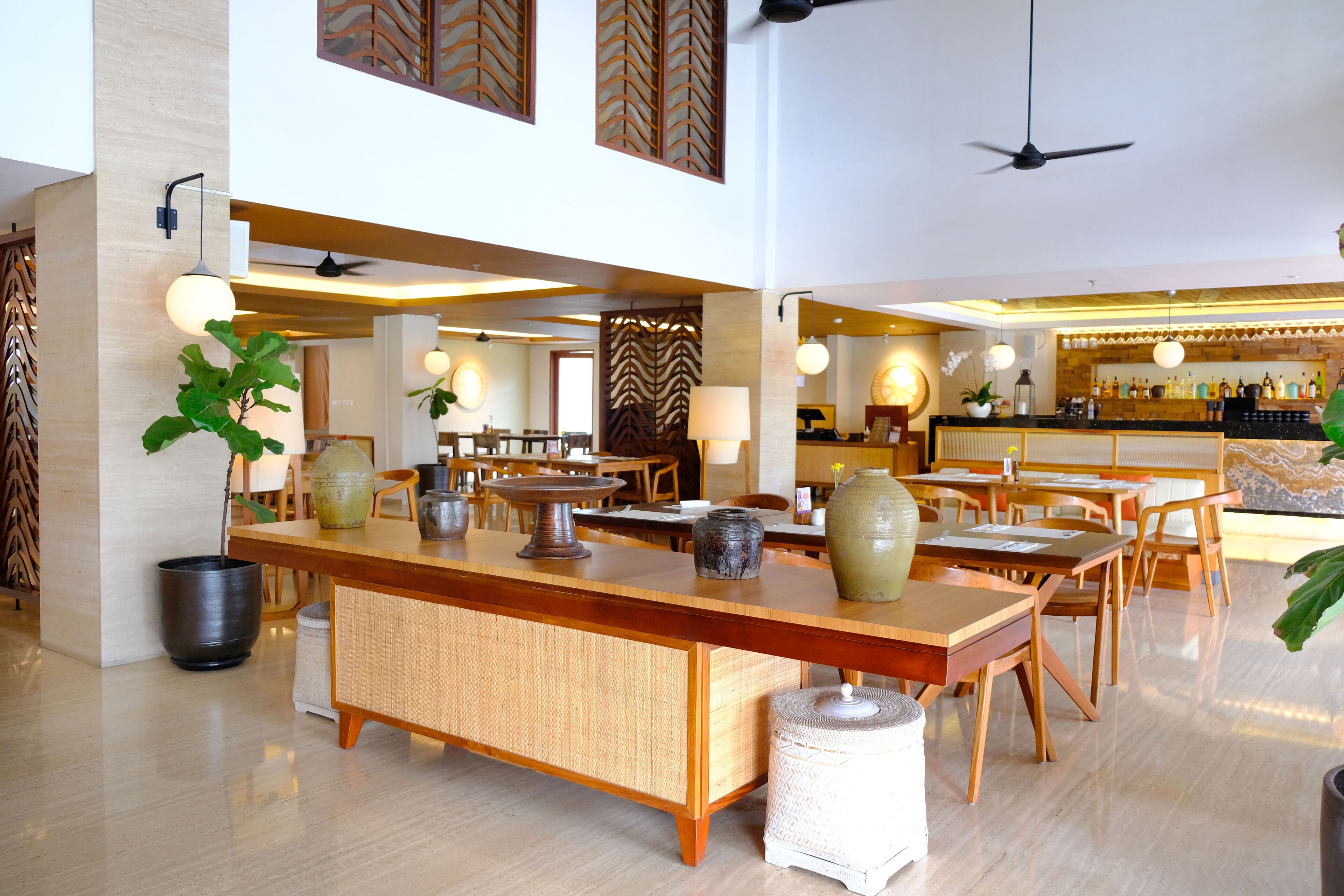 Un hall d’hôtel spacieux doté d’un bar central, de plusieurs espaces aménagés pour s’asseoir et d’un design moderne.