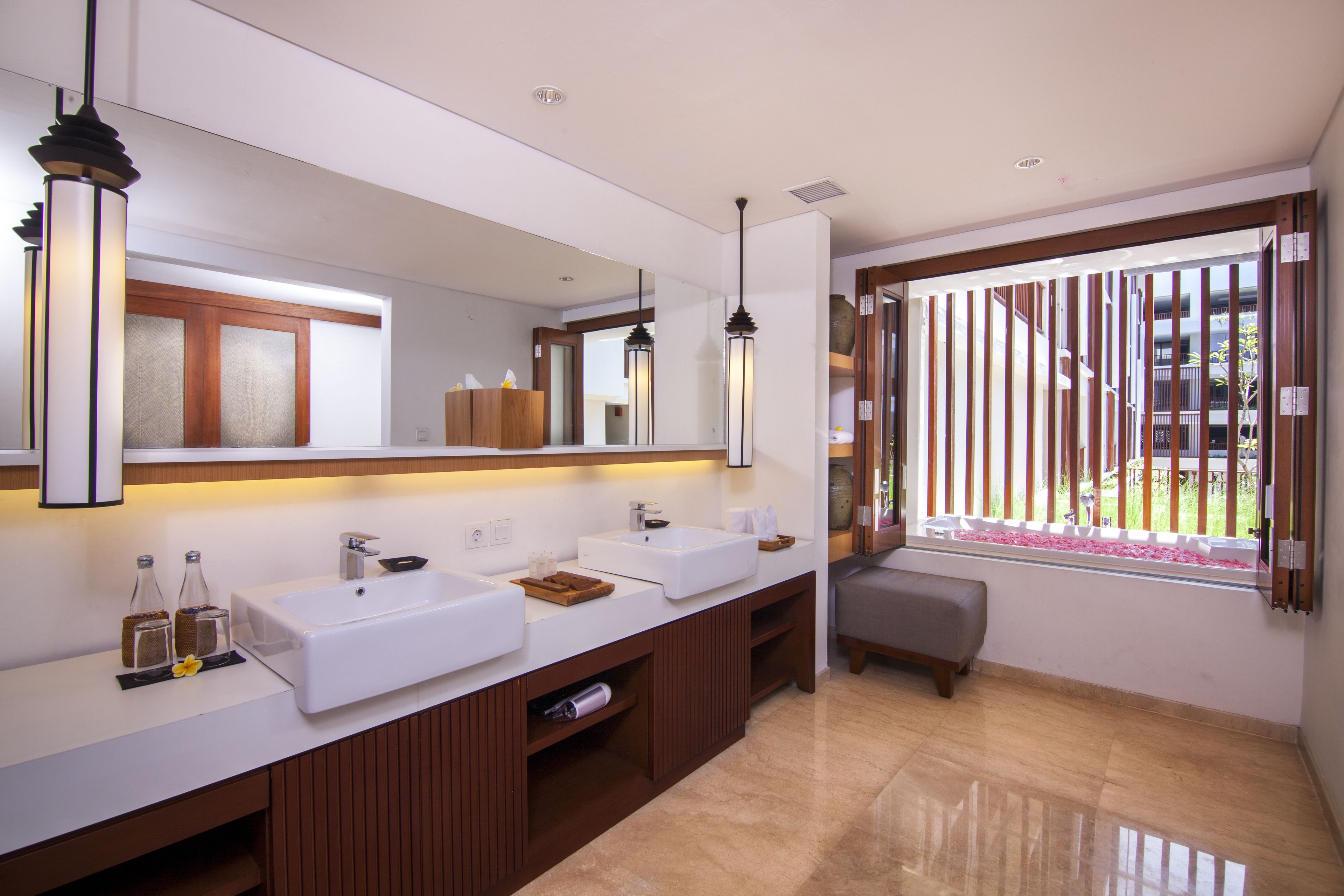 A modern bathroom with two sinks, a large mirror, and a bench by the window.