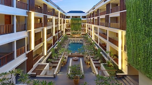 A multi-level hotel atrium with a central pool, balconies, and indoor plants. - The Magani Hotel and Spa (Legian)