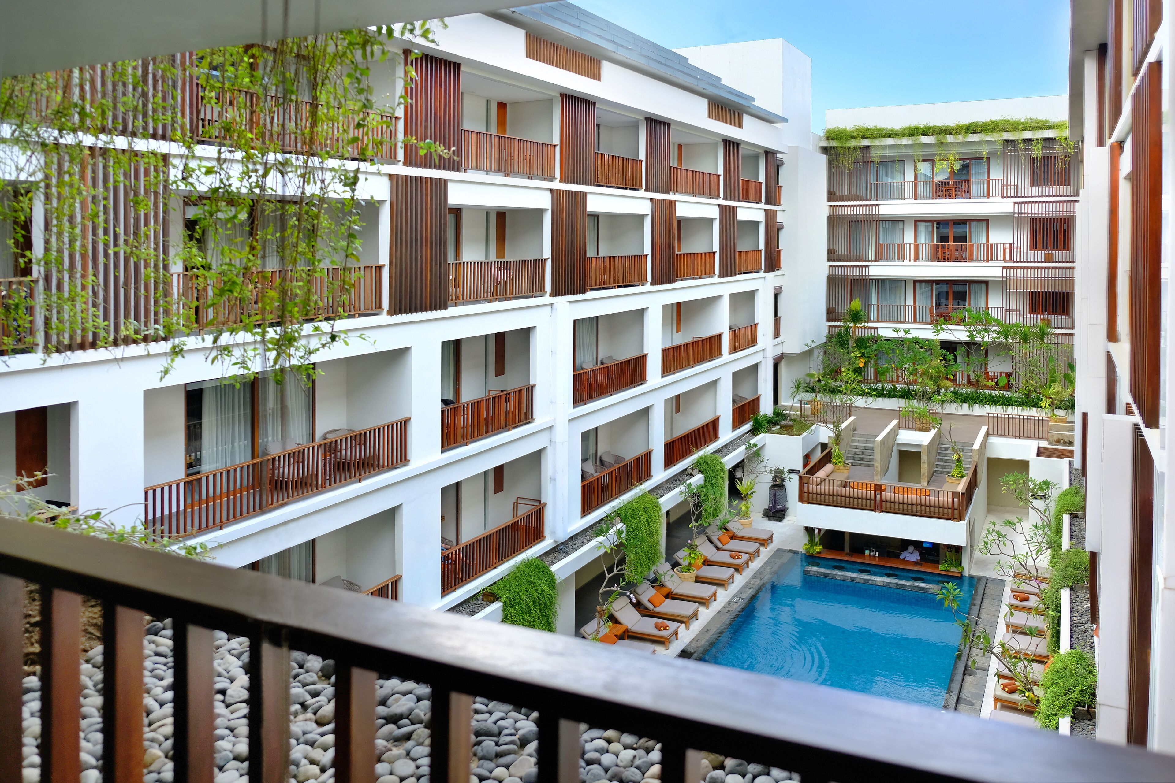 A multi-story hotel with balconies, a swimming pool, and outdoor seating areas.
