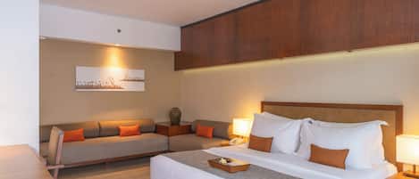 A hotel room with a large bed, a sofa, and a desk.