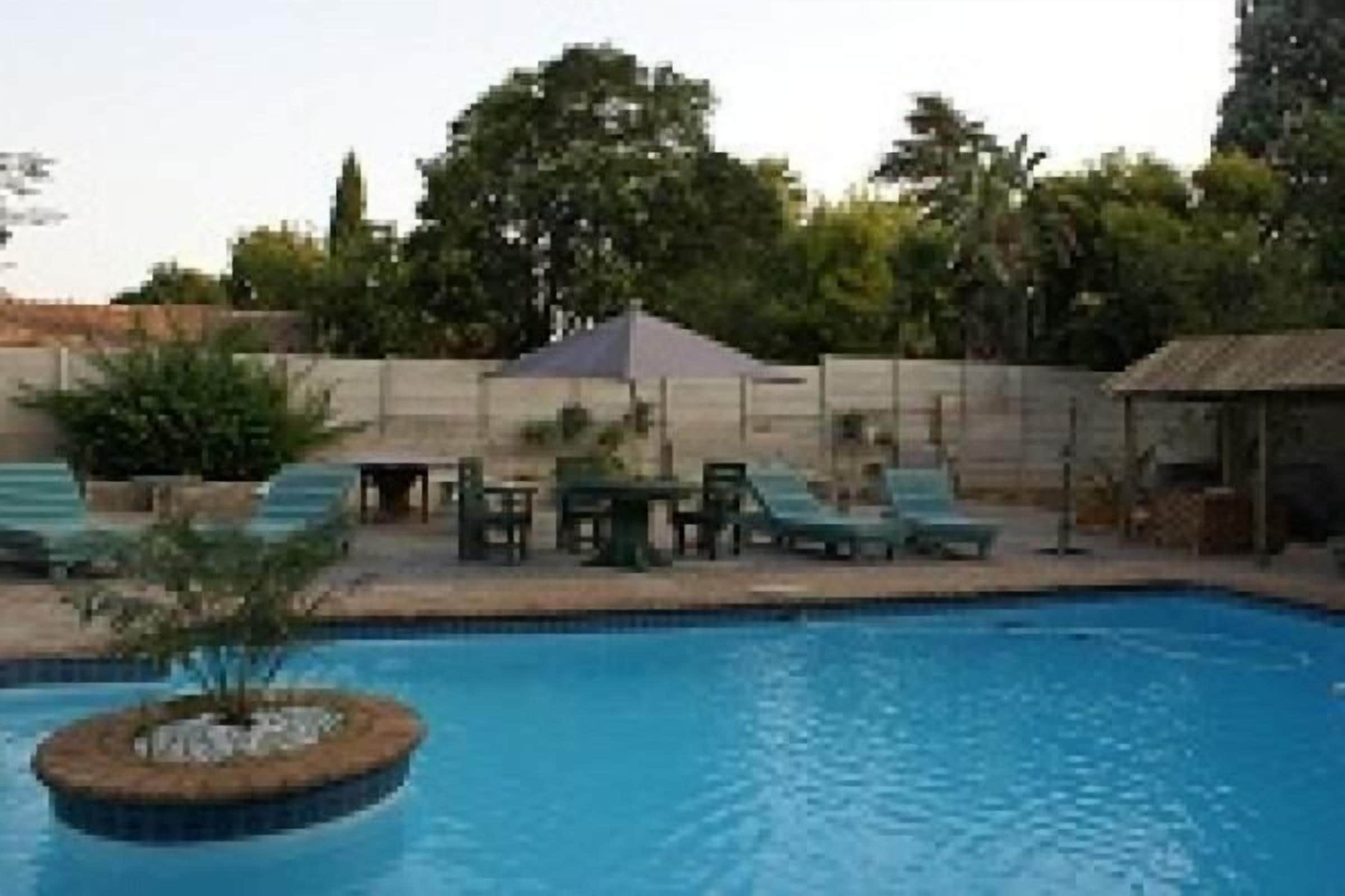 Een buitenzwembad, ligstoelen bij het zwembad