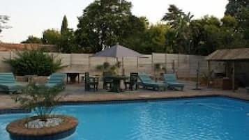 Een buitenzwembad, ligstoelen bij het zwembad