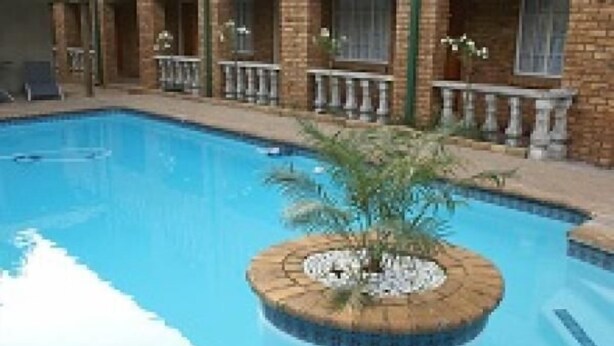 A swimming pool with a circular island in the center, surrounded by a brick building with balconies.