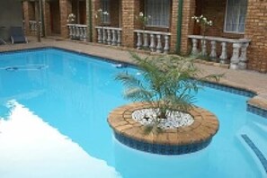 Una piscina con una isla circular en el centro, rodeada por un edificio de ladrillo con balcones.