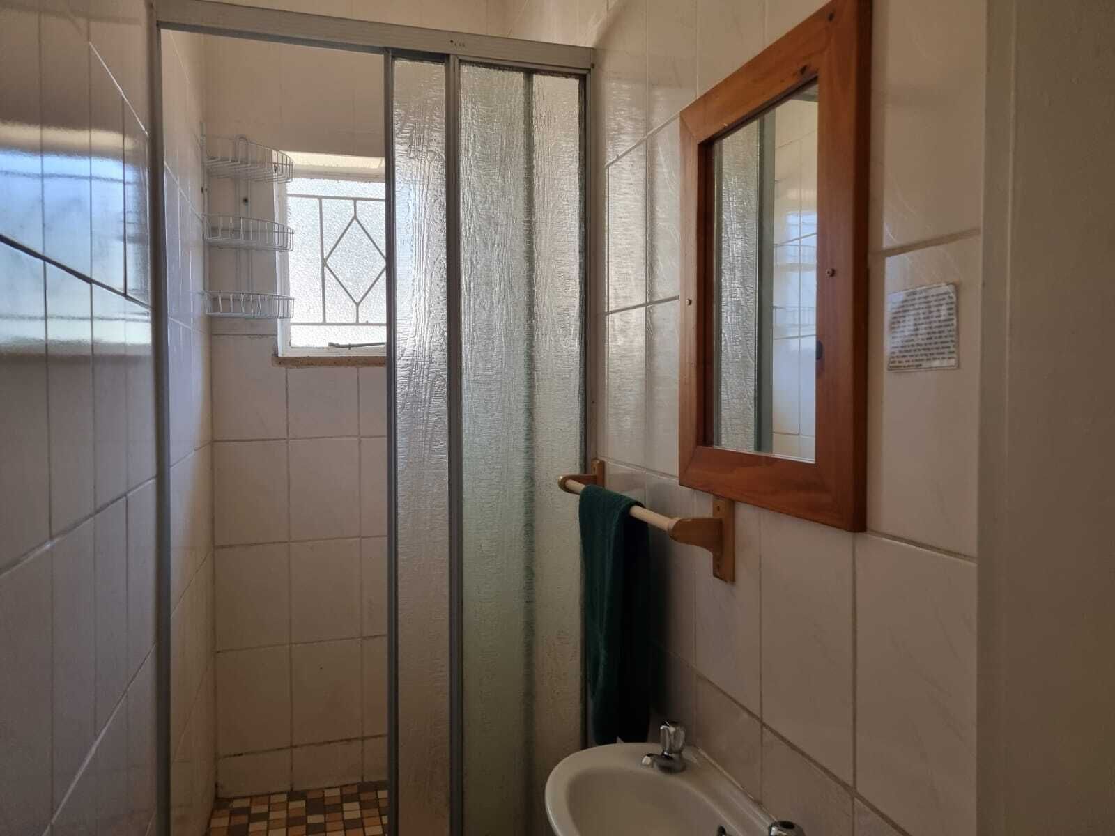 Un baño con ducha, lavamanos y espejo.