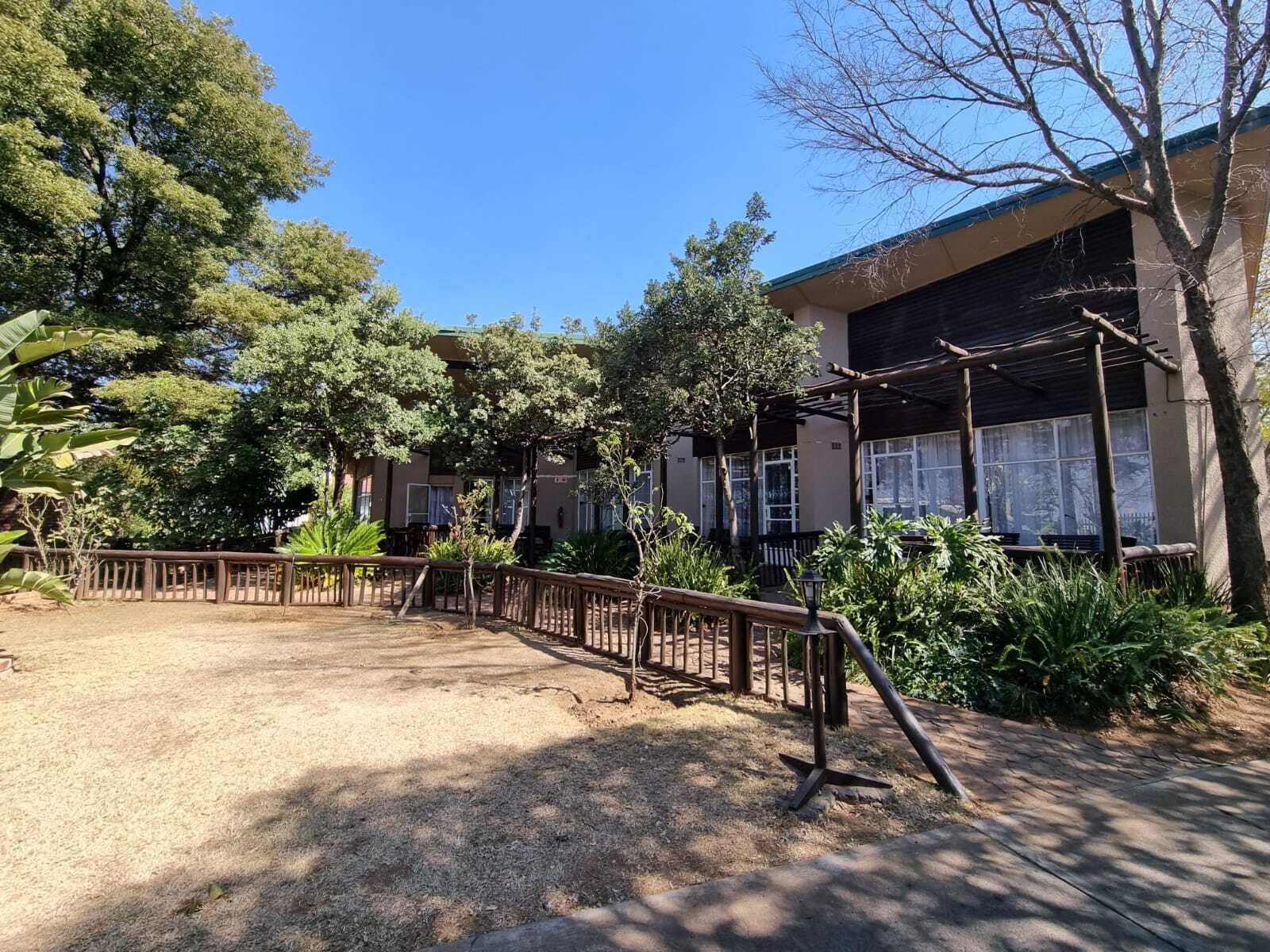 Une cour avec une clôture en bois, une pergola et un bâtiment doté de grandes fenêtres.