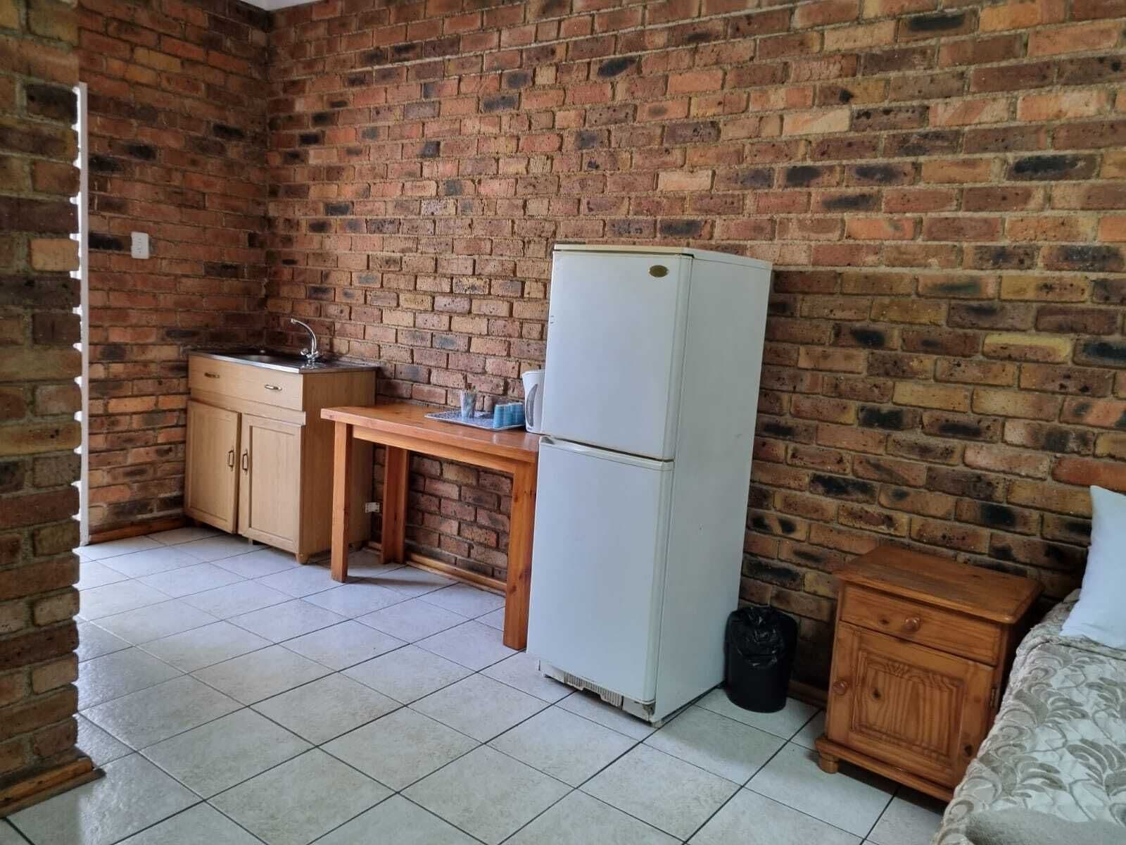 A compact kitchen with a refrigerator, a wooden table, and a sink.