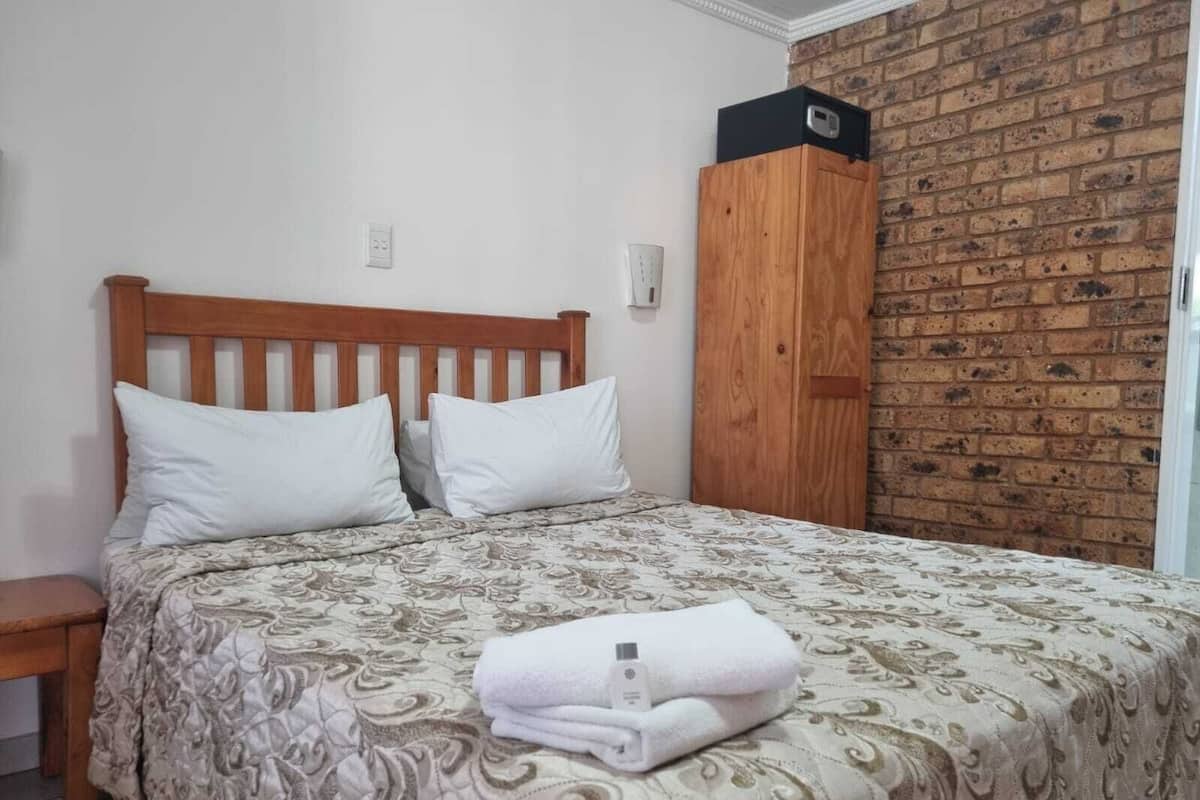 Un lit avec une couvre-lit à motifs, deux oreillers et une serviette pliée posée sur le lit.