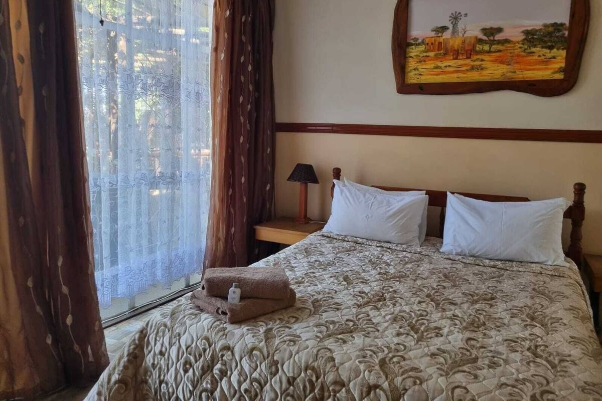 Une chambre d’hôtel avec un lit, une table de chevet, une lampe et un tableau au mur.