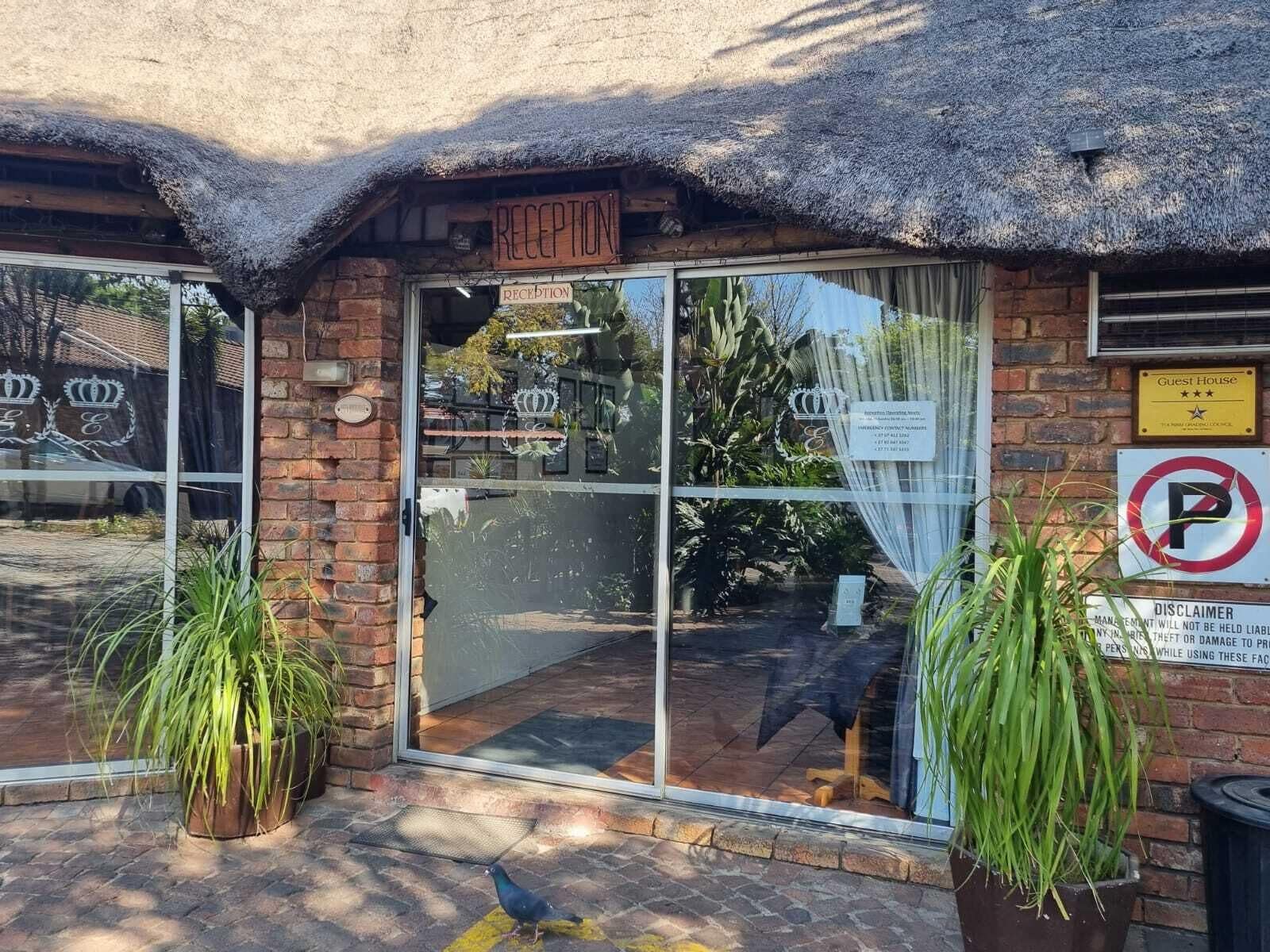A reception area with a thatched roof, a glass door, and a "Guest House" sign.