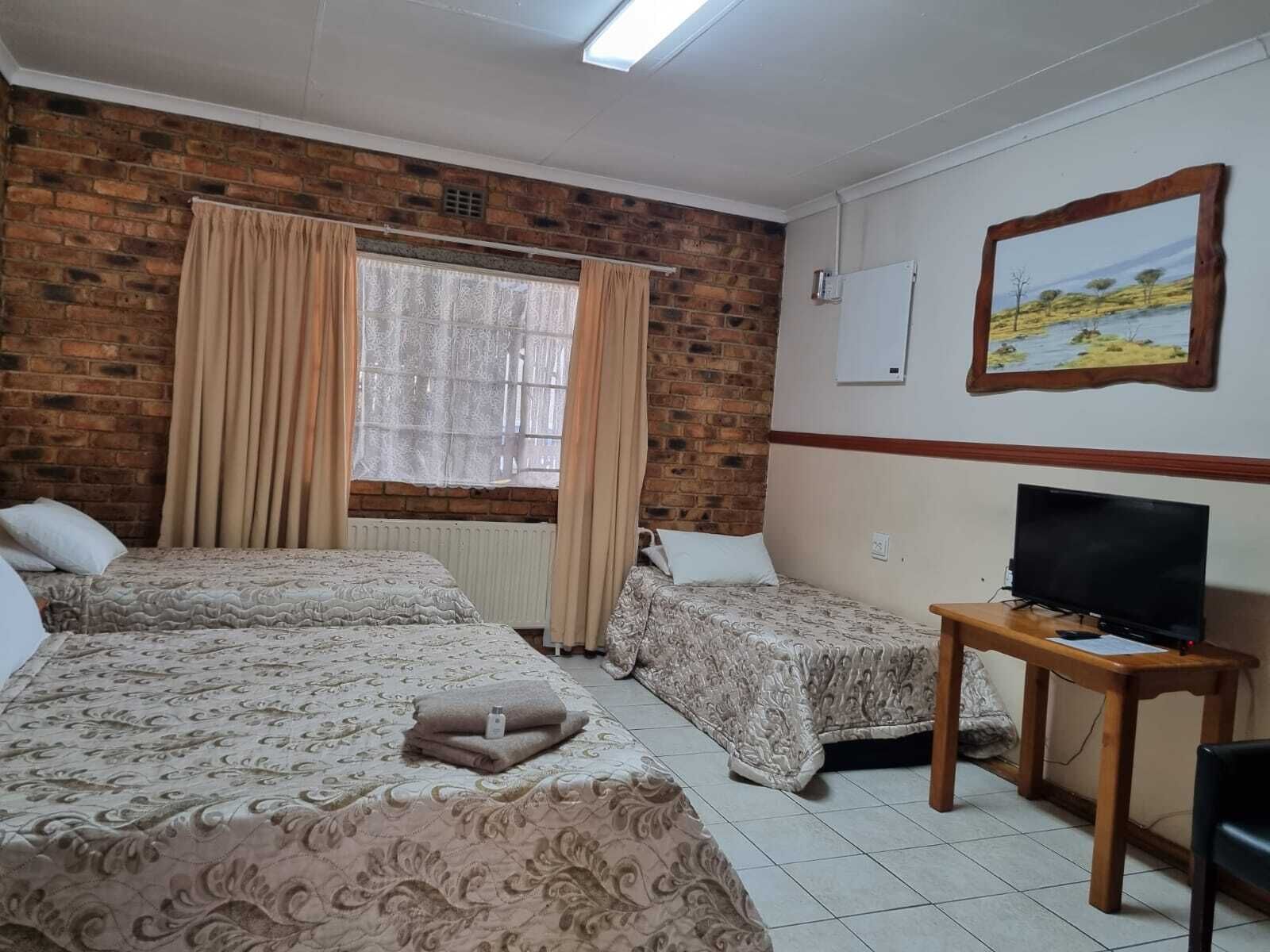 Een hotelkamer met twee bedden, een televisie en een schilderij aan de muur.
