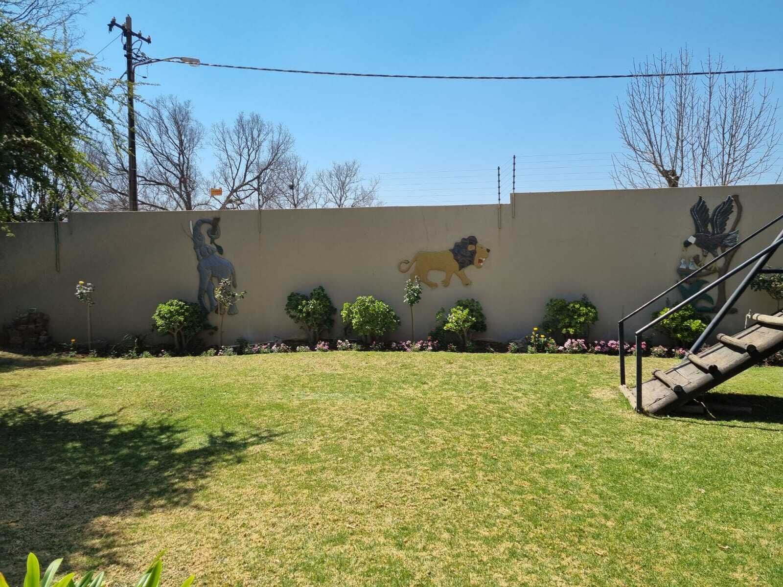 A grassy area with a mural of a lion and a horse, a staircase, and a wall with power lines.