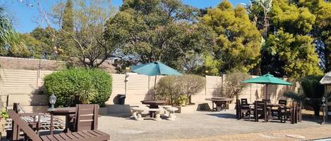 Zona de piscina con sillones, una mesa y sombrillas.