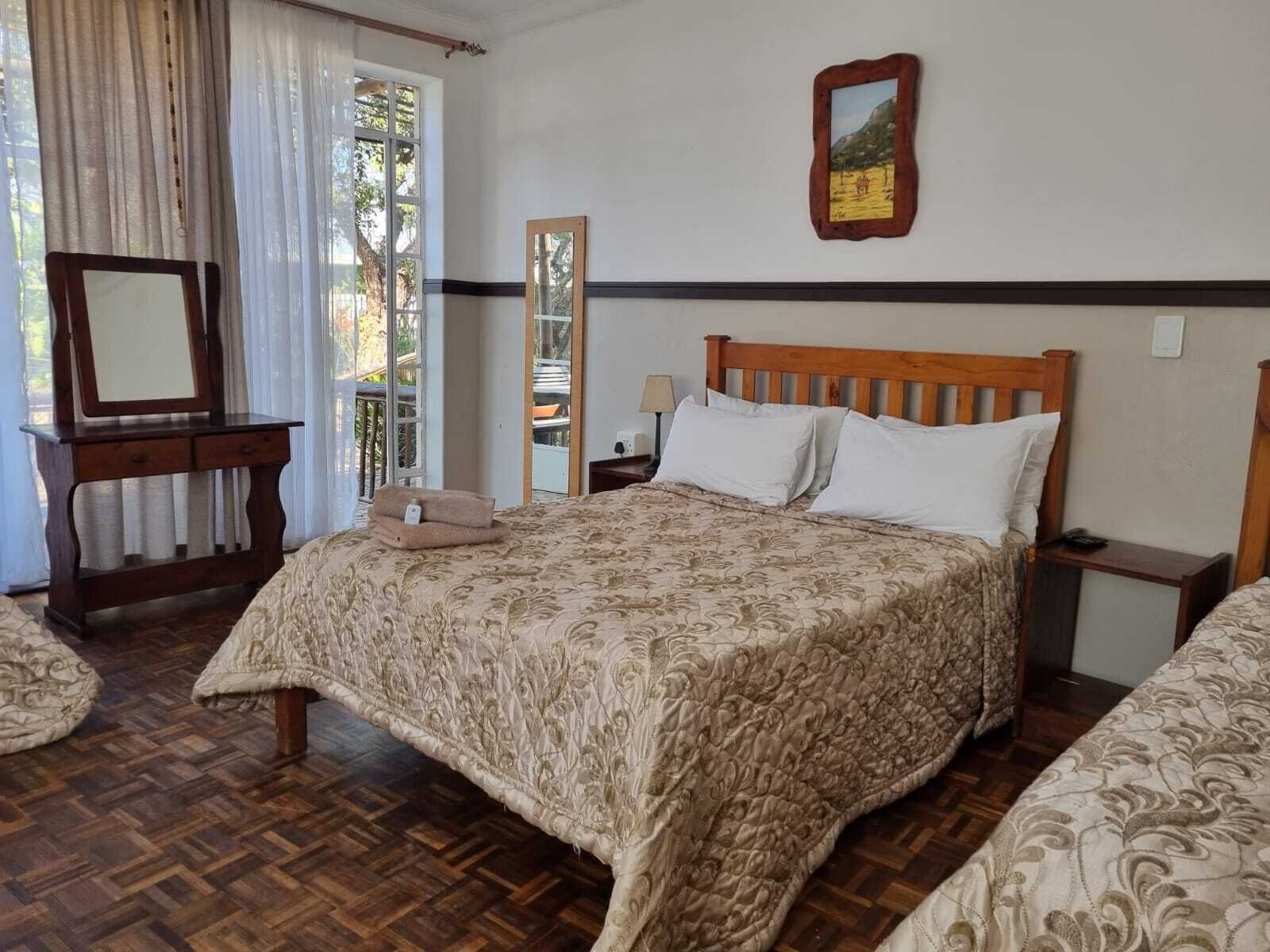 A bedroom with a wooden bed, a bedside table, a mirror, and a window with curtains.