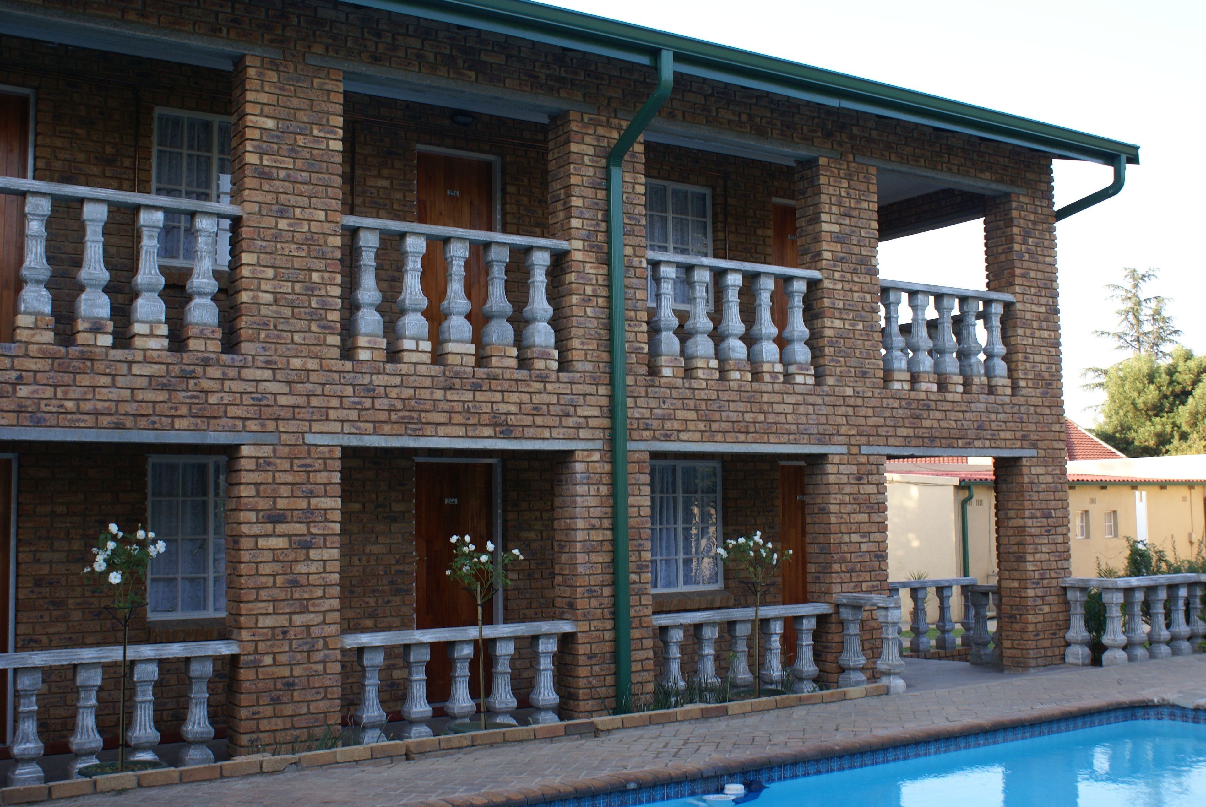A multi-story brick building with balconies and a swimming pool.