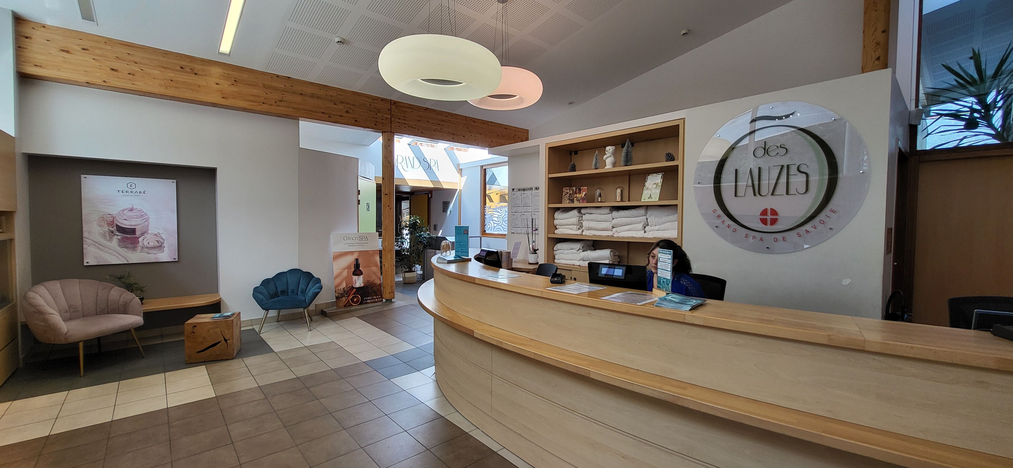 A reception area with a wooden reception desk, a blue chair, and a wall with a circular sign.