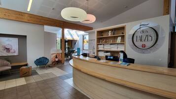 A reception area with a wooden reception desk, a blue chair, and a wall with a circular sign.