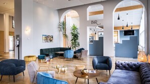 A modern lobby with a bar area, seating arrangements, and a large plant.