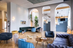 Eine moderne Lobby mit Barbereich, Sitzgelegenheiten und einer großen Pflanze.