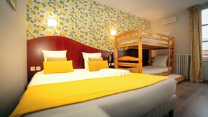 Ein Hotelzimmer mit einem Etagenbett, einem großen Bett mit gelber Bettwäsche und einer Wand mit Zitronenmuster.