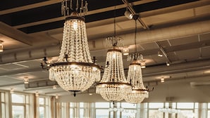 A bar area with a curved counter, multiple bar stools, and hanging crystal chandeliers. - Smögens Hafvsbad (Smogen)