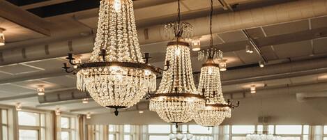 A bar area with a curved counter, multiple bar stools, and hanging crystal chandeliers.