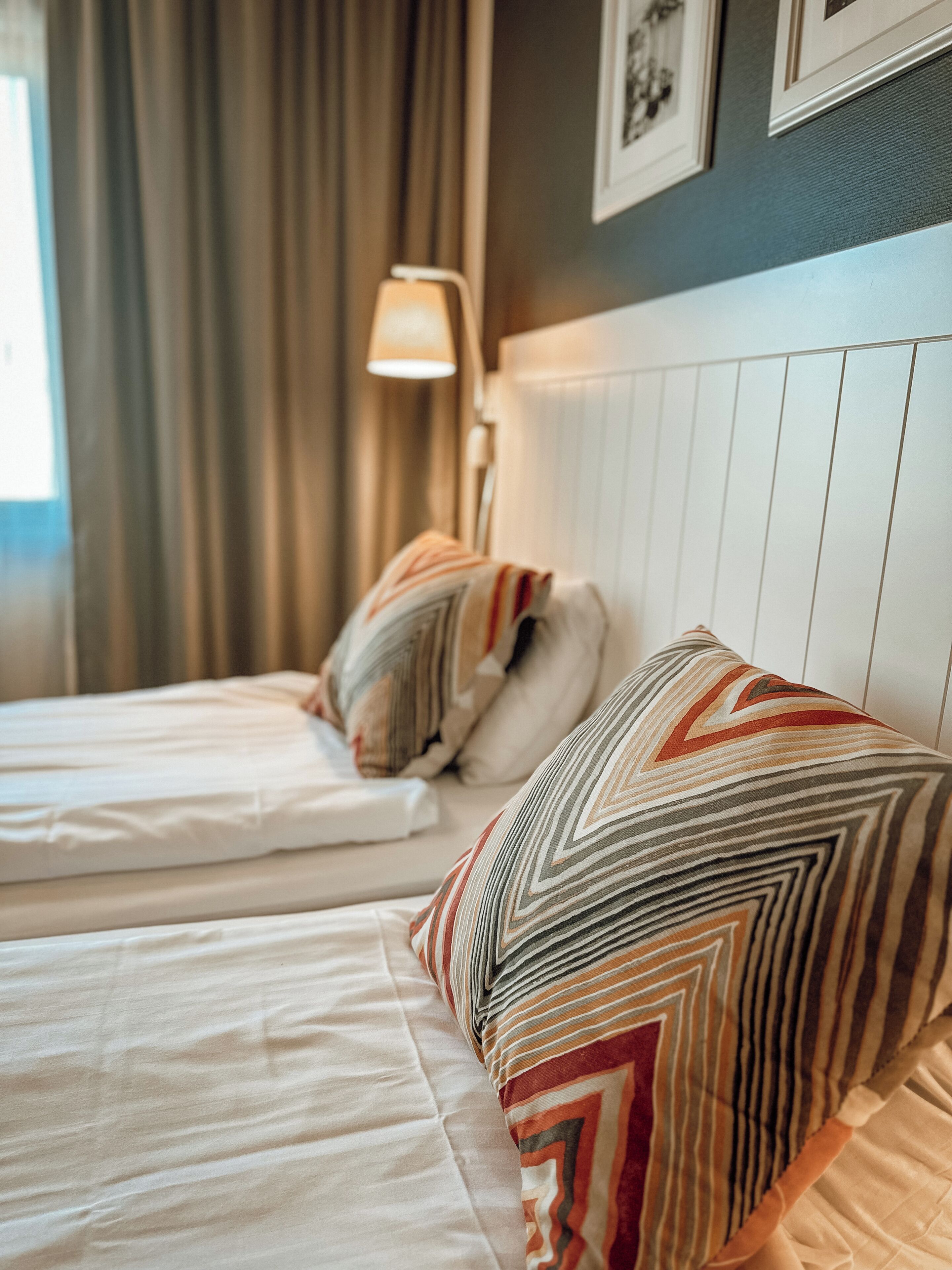 Une chambre d’hôtel avec deux lits, une lampe et un tableau encadré au mur.