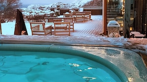 A pool area with a wooden deck, benches, and string lights. - Smögens Hafvsbad (Smogen)