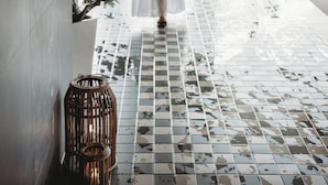 A person in a white robe walking through a hallway with tiled flooring and a potted plant. - Smögens Hafvsbad (Smogen)
