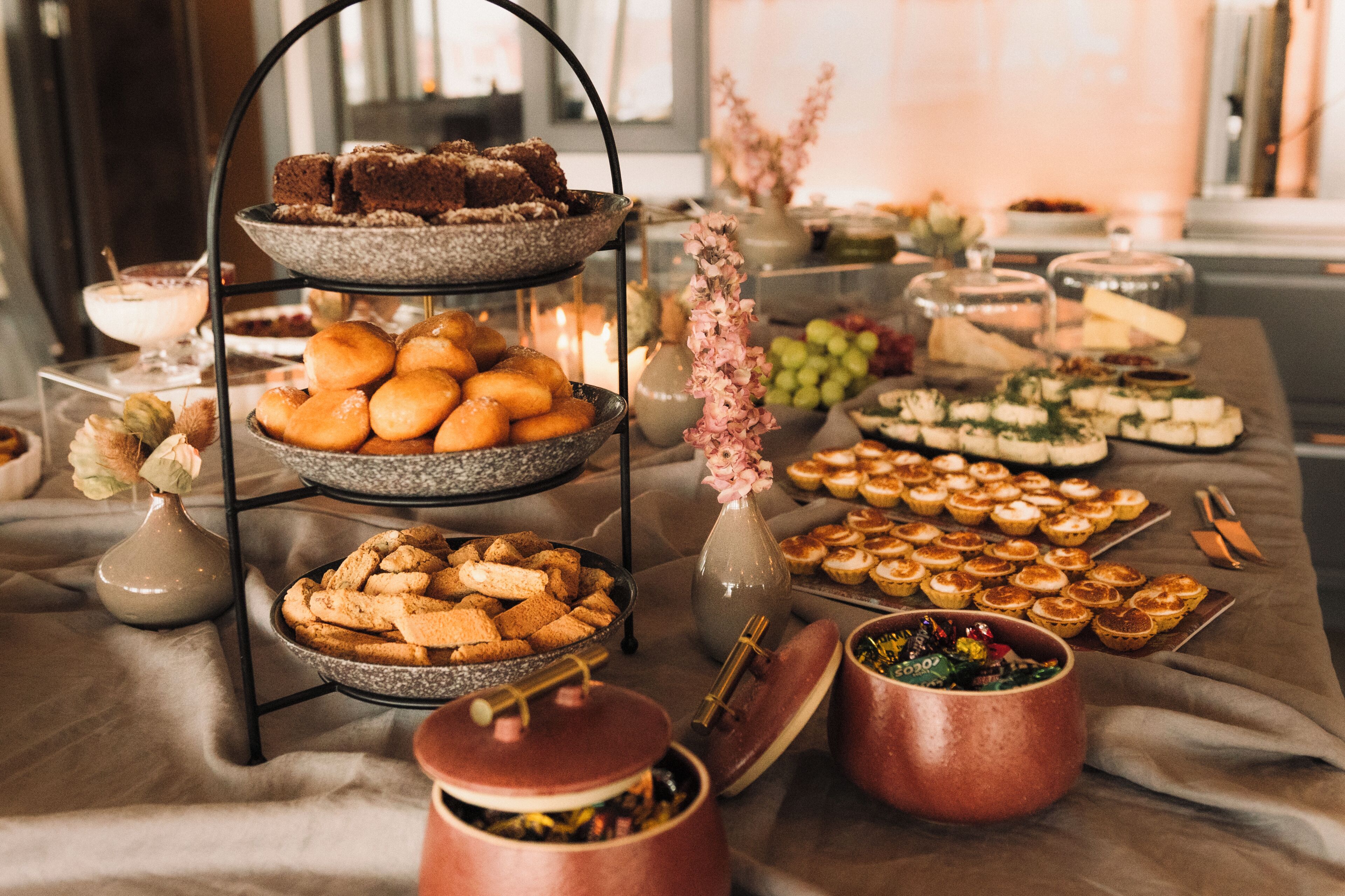 A buffet table with various food items and a tiered serving stand.