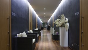 A hallway with dark walls, wooden flooring, and black wicker sofas with white cushions.