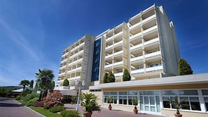 A multi-story hotel with a modern design, featuring a central courtyard with potted plants and a clear sky.