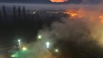 Nachtsicht auf eine Berglandschaft mit dichter Nebelstimmung und entfernten Stadtlichtern.
