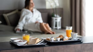 A breakfast tray with bread, pastries, and juice on a table in a hotel room.