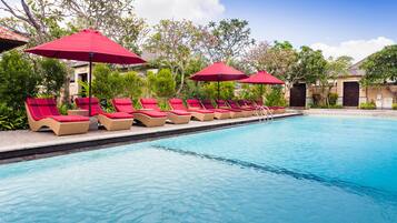 Una piscina al aire libre, sombrillas, sillones reclinables de piscina