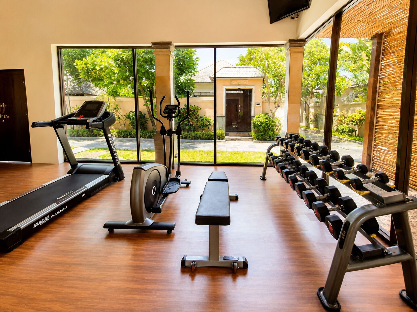 A gym with treadmills, an elliptical, a bench, and dumbbells.