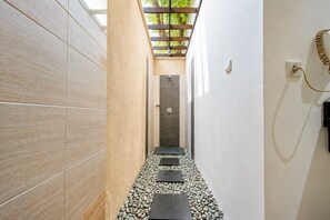 A narrow hallway with tiled walls, a shower area, and a telephone. - Aldeoz Grand Kancana Villa Bali (Keroboken Kelod)