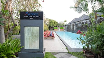 Una piscina al aire libre, sombrillas, sillones reclinables de piscina