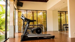 A home gym with a treadmill, dumbbells, and a stationary bike.
