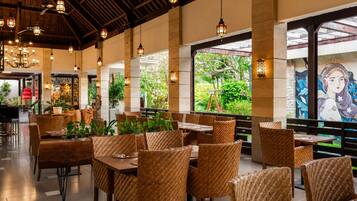 A restaurant with wicker furniture, hanging lanterns, and a mural on the wall.