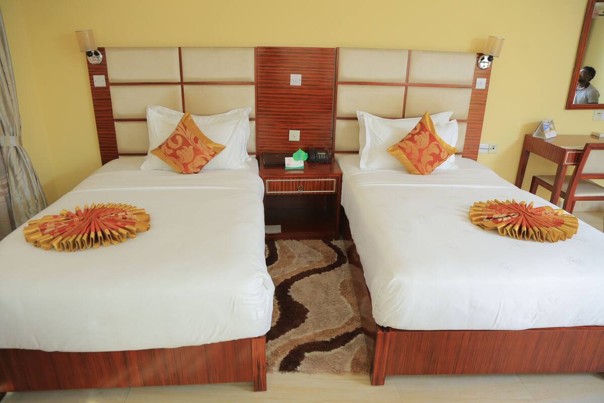 A hotel room with two beds, a nightstand, a desk, and a chair.