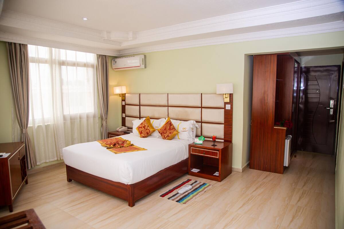A hotel room with a large bed, bedside tables, a desk, and a wardrobe.