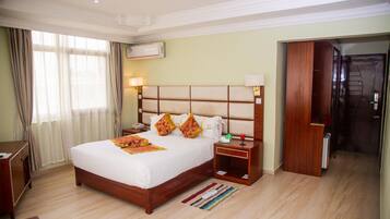 A hotel room with a large bed, bedside tables, a desk, and a wardrobe.